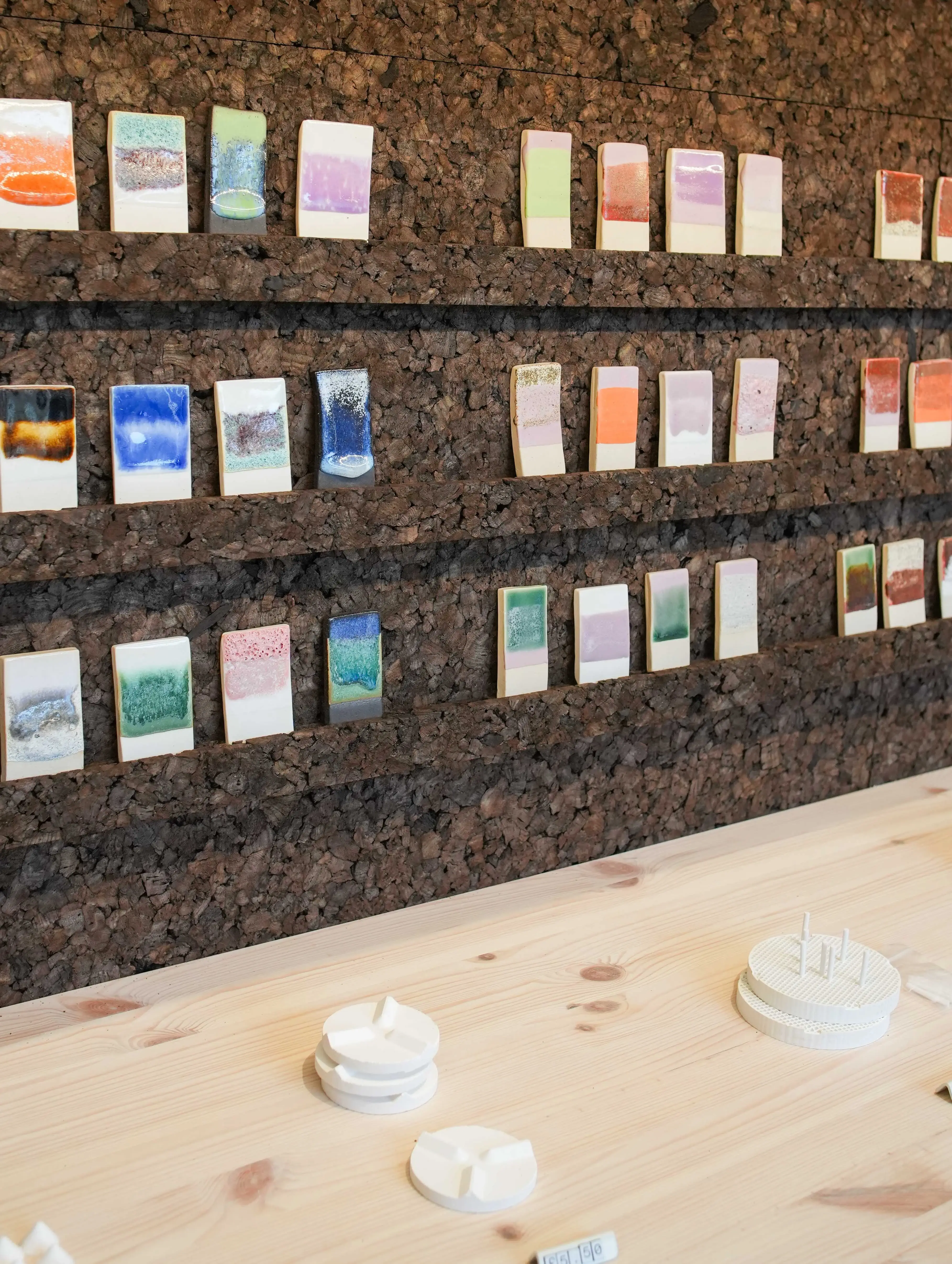 Ceramic glaze test tiles displayed on cork wall at GLOST glaze shop London